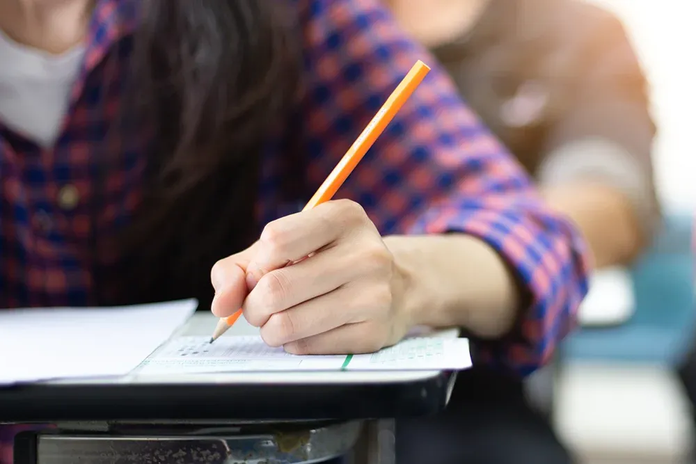 A student filling in a bubble on a paper test sheet representing.